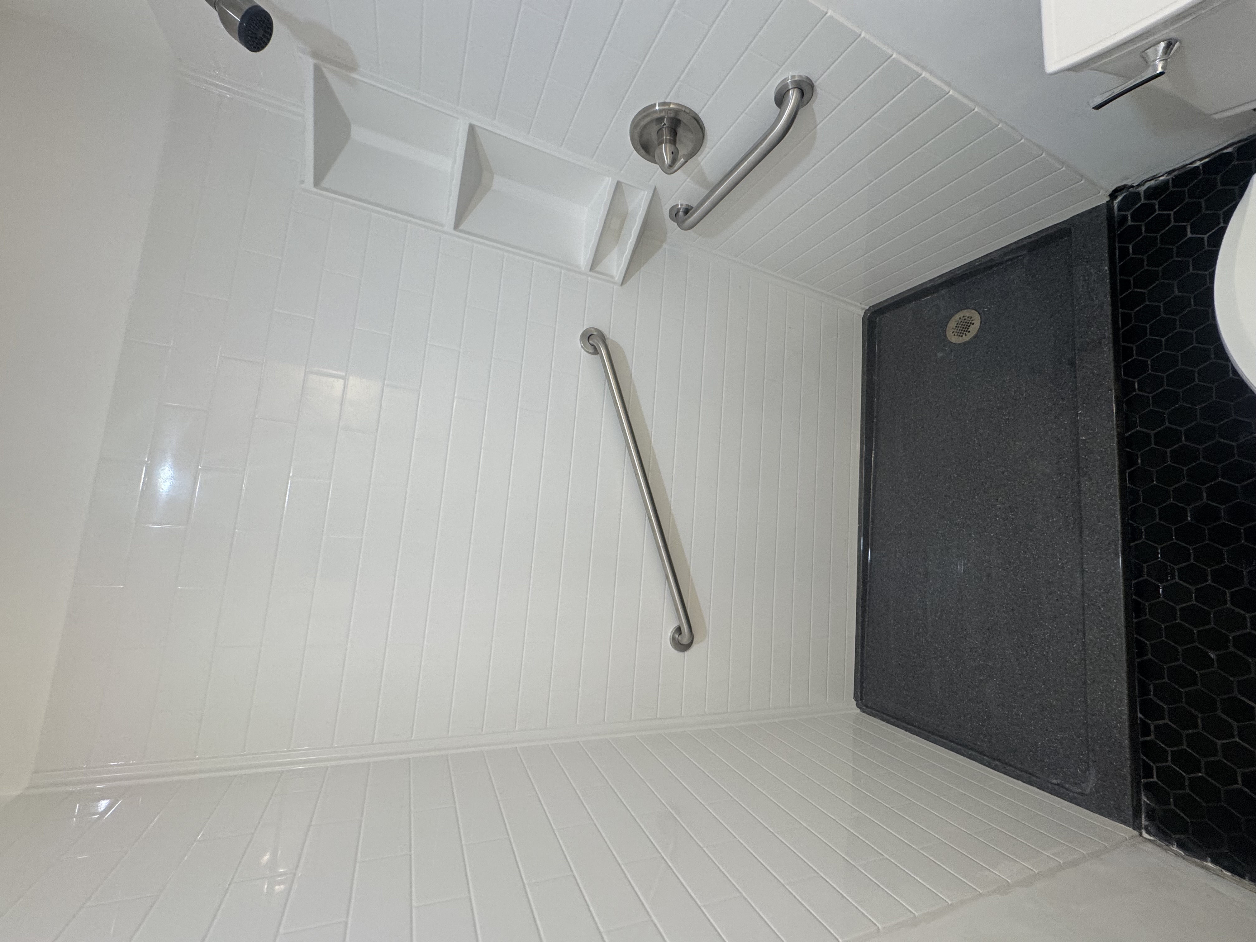 Finished white subway-pattern Onyx shower with charcoal base